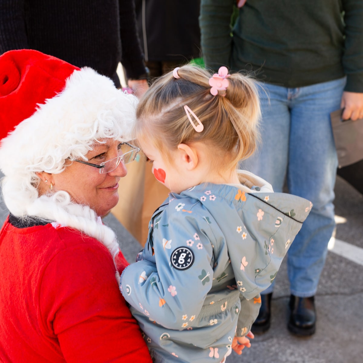 Marché de Noël de Prévost - Une femme déguisée en Mère Noël tient un enfant dans ses bras.