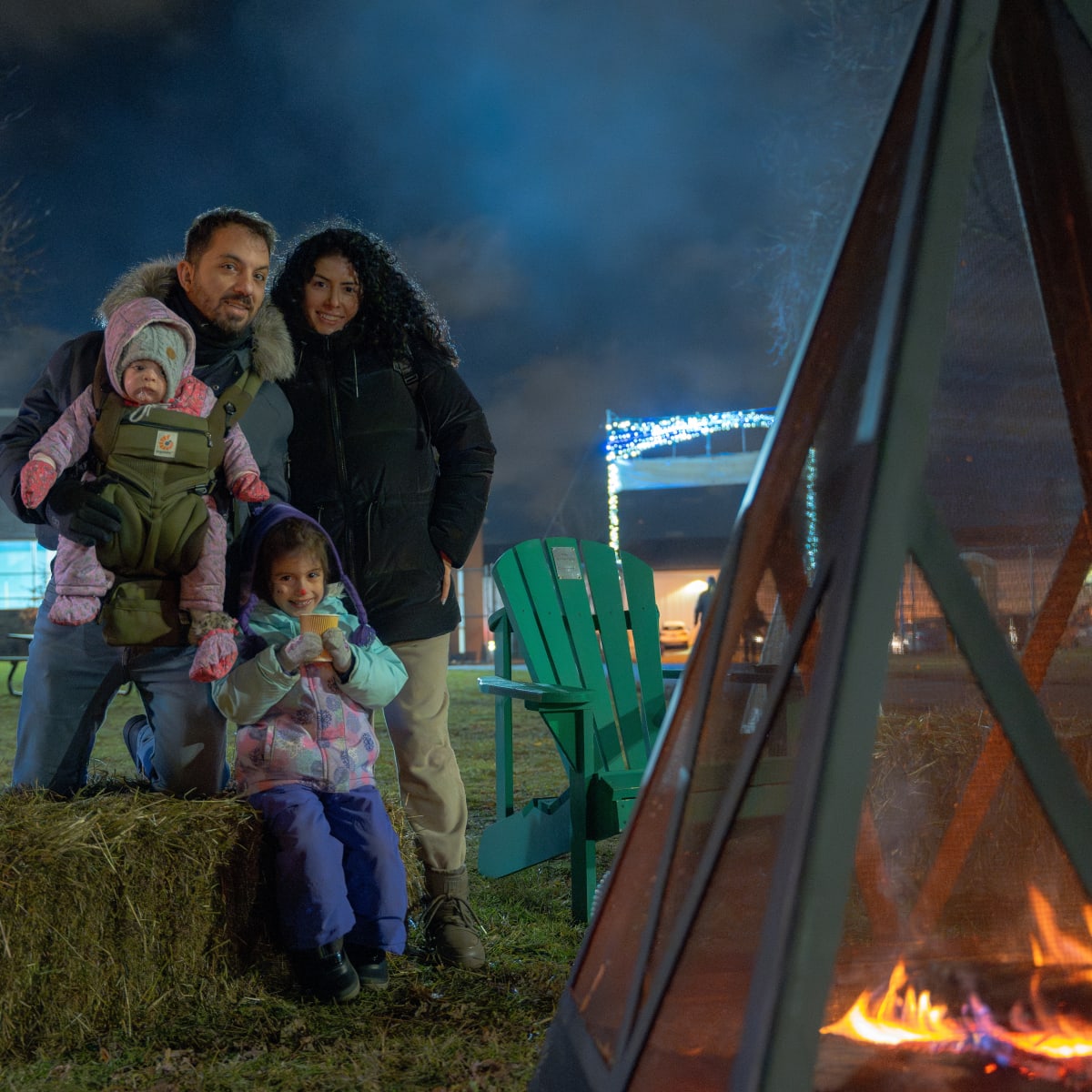 Une famille se réchauffe devant un feu de camp.
