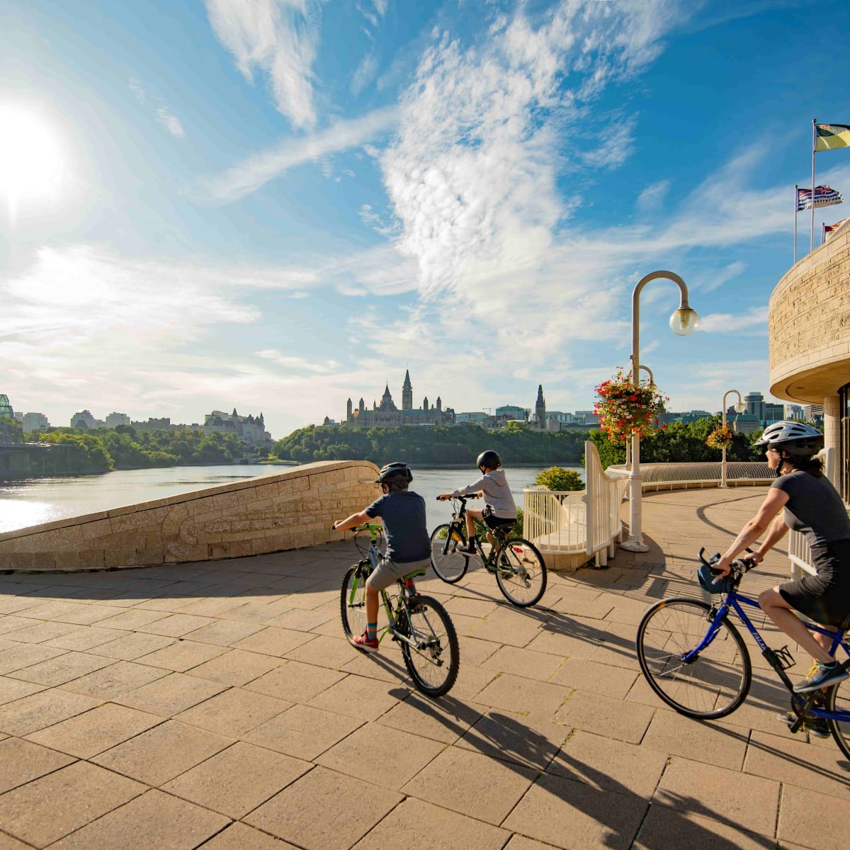 Parent et deux enfants en vélo à l'extérieur du Musée canadien de l'histoire