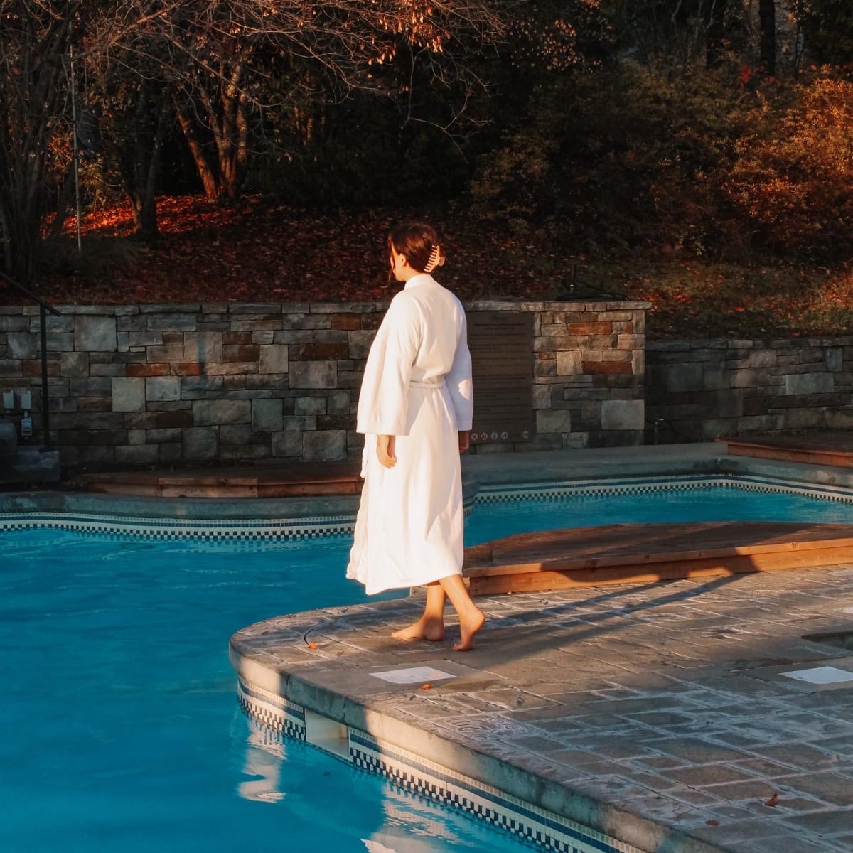 Femme en peignoir au bord de la piscine du Fairmont Le Manoir Richelieu en automne