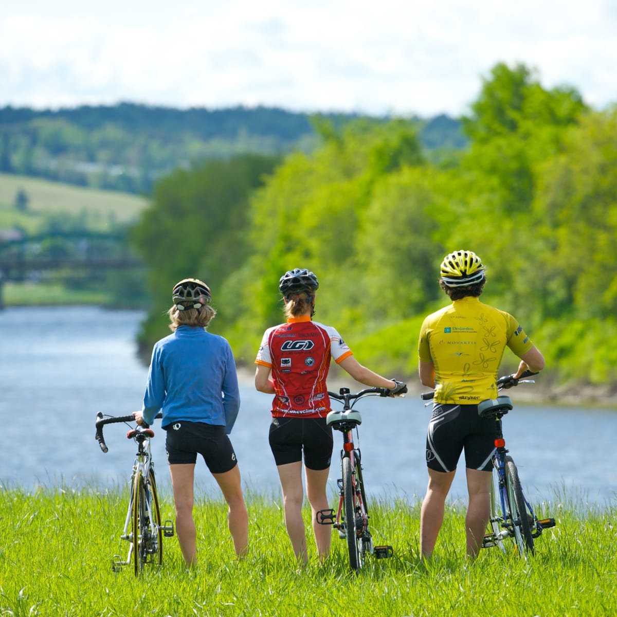 Trois cyclistes au bord de l'eau qui admirent le paysage.