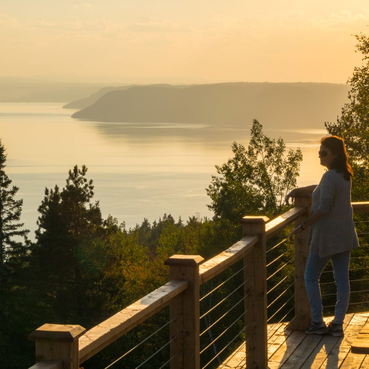 Femme regardant une vue panoramique du Fjord au coucher du soleil.