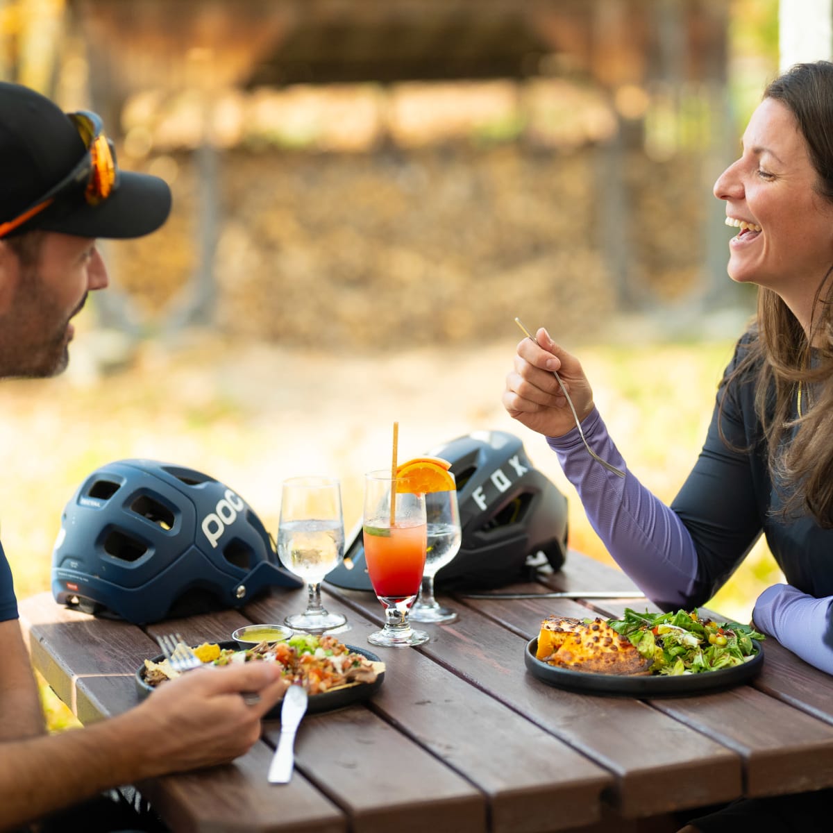 A couple laughing at a table on an autumn terrace.