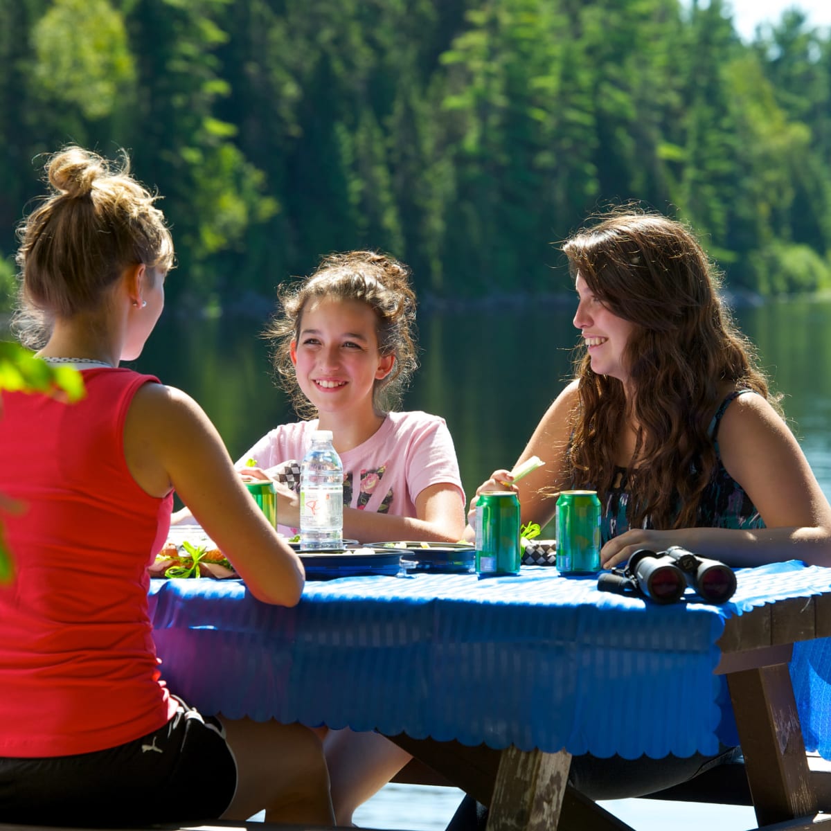2 femmes et une jeune fille en pique-nique sur le bord d'un lac.
