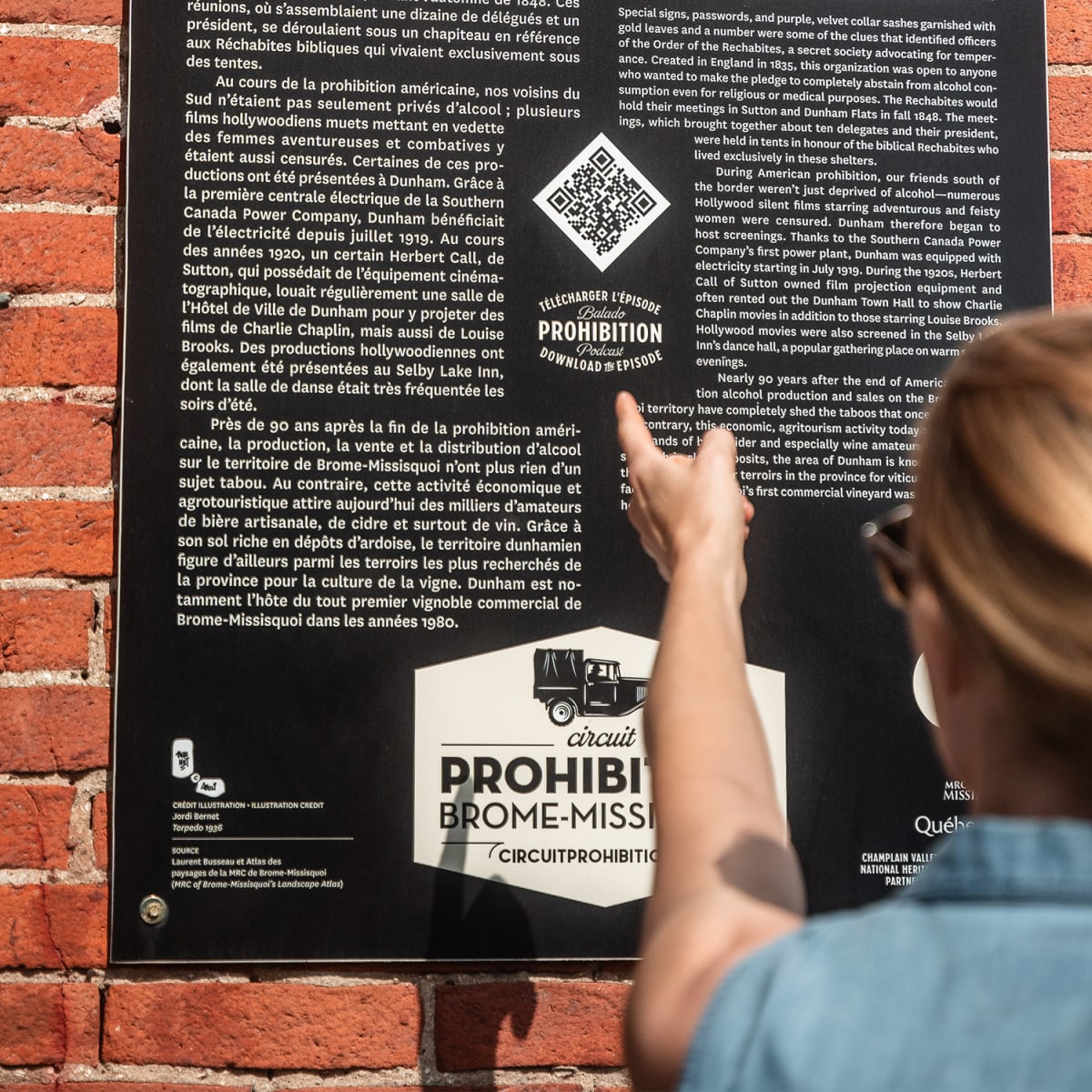 Femme qui lit un panneau sur la route de la Prohibition dans Brome-Missisquoi.