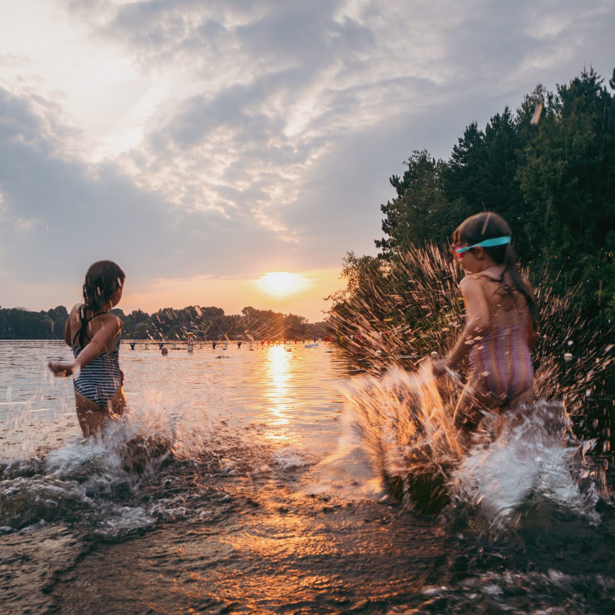 Young kids in the water as the sun is going down.