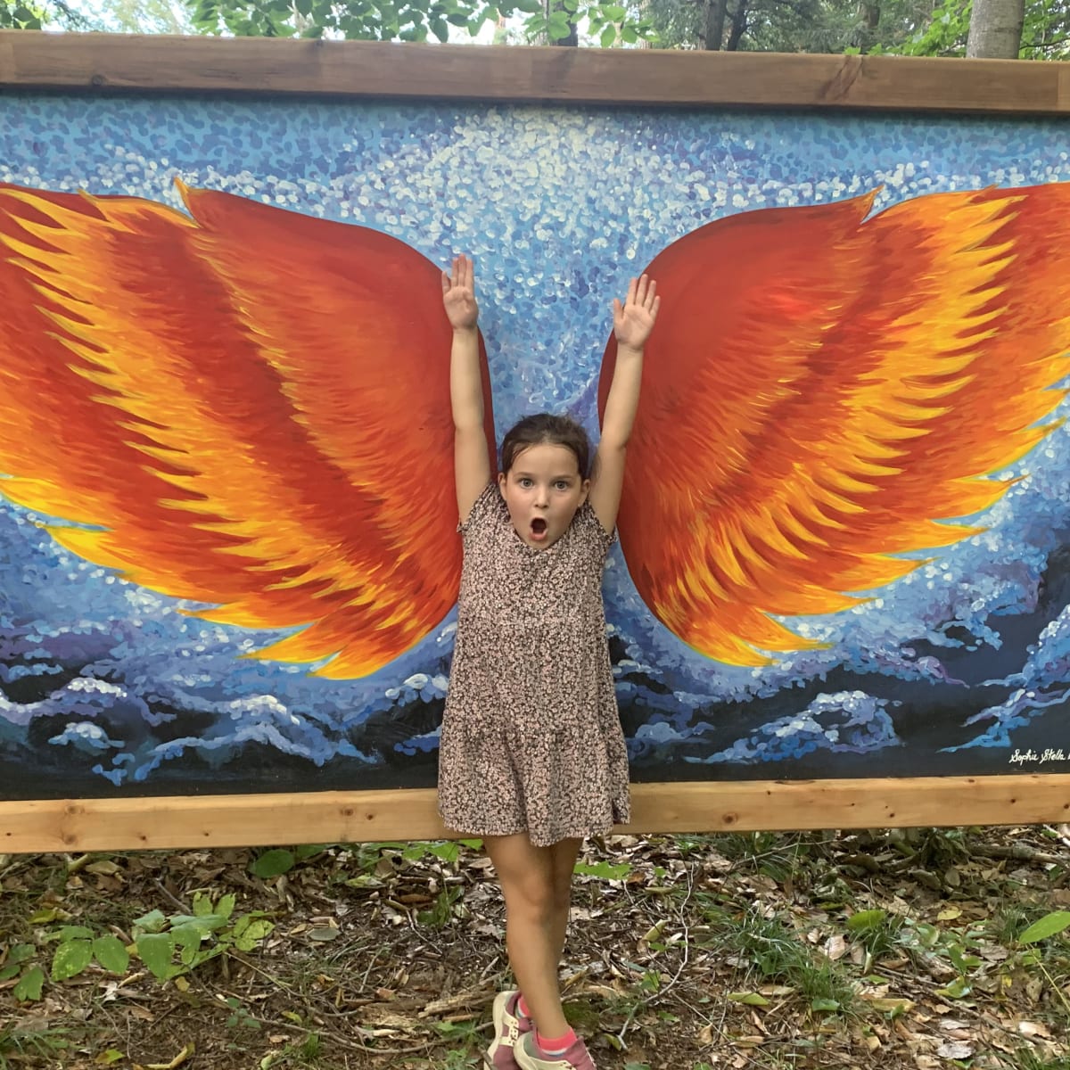 Young girl striking a pose in front of drawn wings.