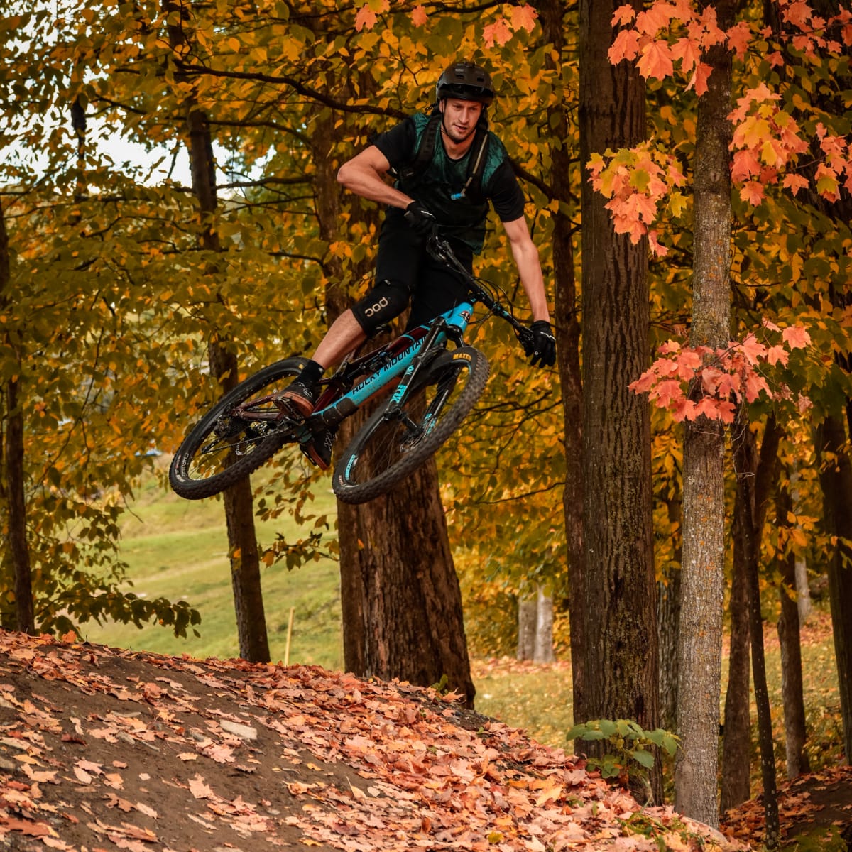 Mountain biker making a jump in a fall setting.