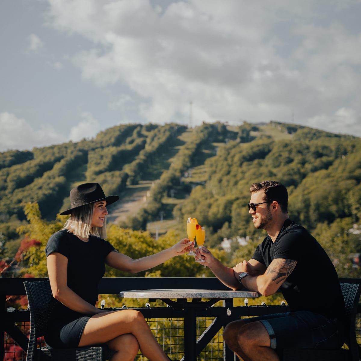 Couple sharing a drink in front of the ski hill in late summer.