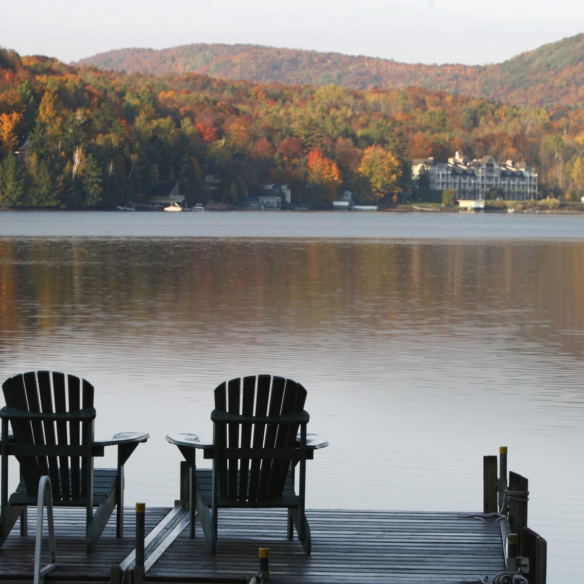 Two patio chairs on a deck in front of Lake Massawippi.