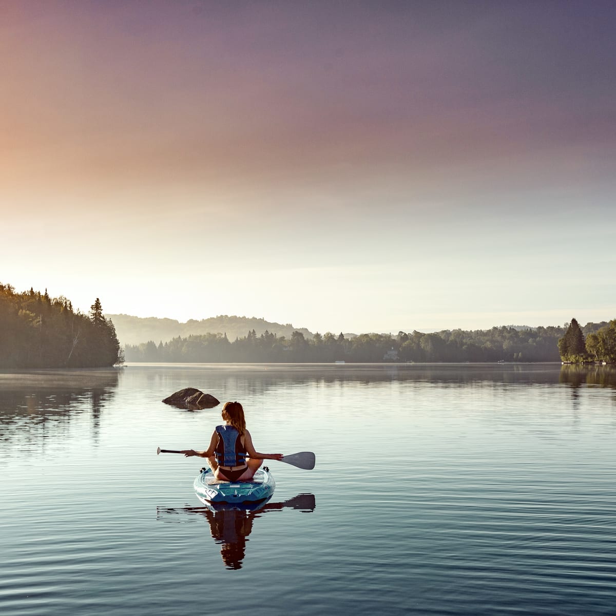 Woman on the lake on a paddleboard at Estérel Resort.