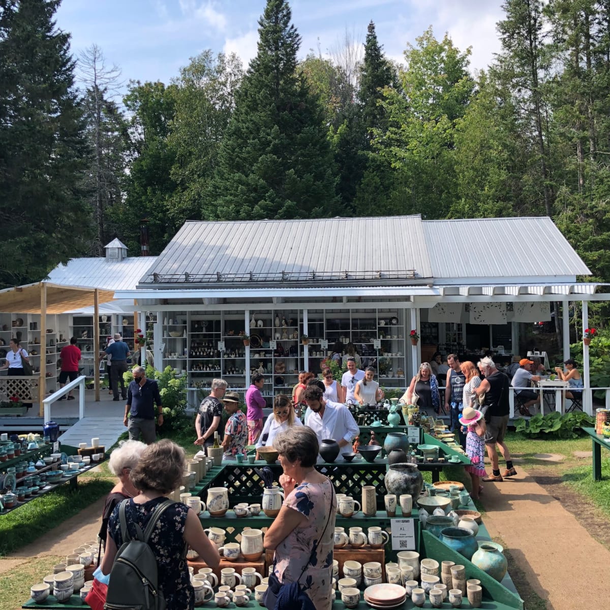 The exhibition site, with a small house and outdoor tables filled with ceramics.
