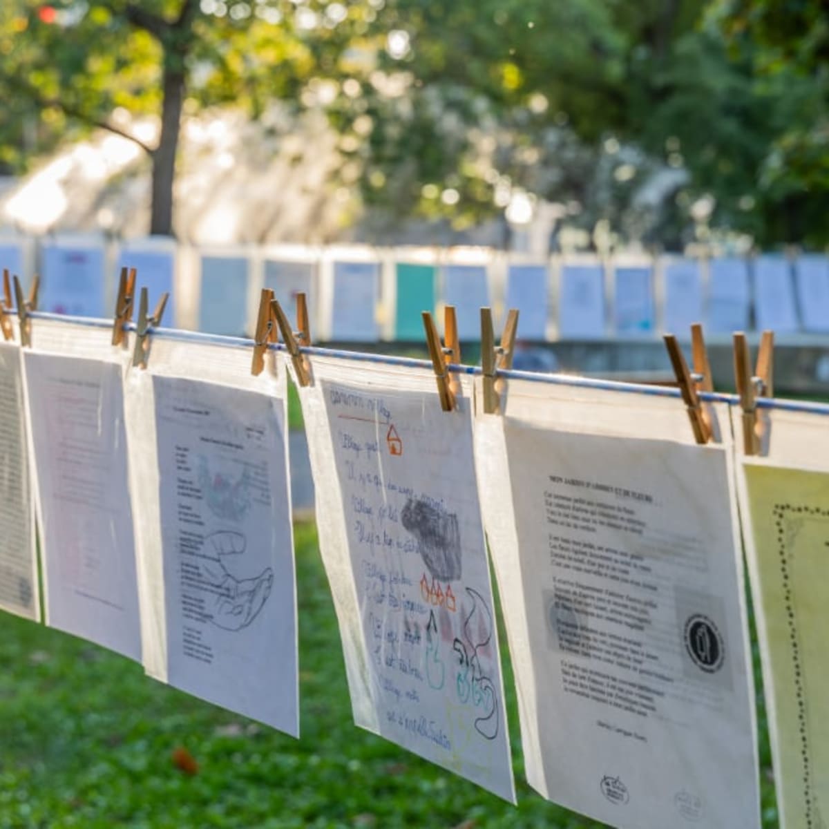 Rope stretched between trees on which papers with poems written on them have been clipped.