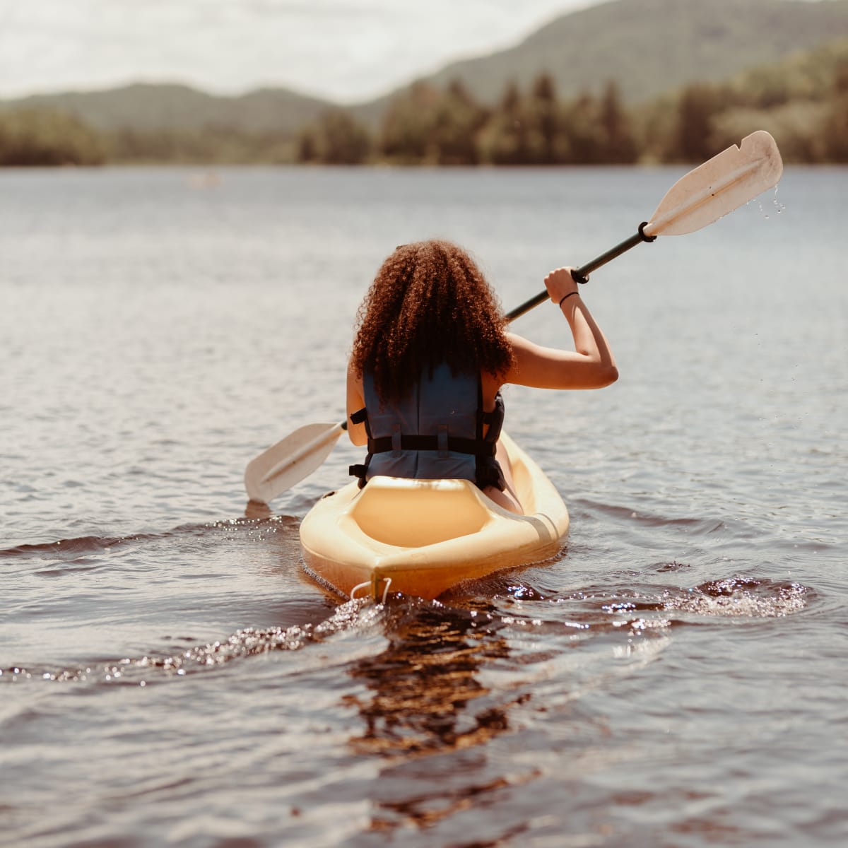 Jeune femme en kayak sur le lac. Young woman in a kayak on the lake.