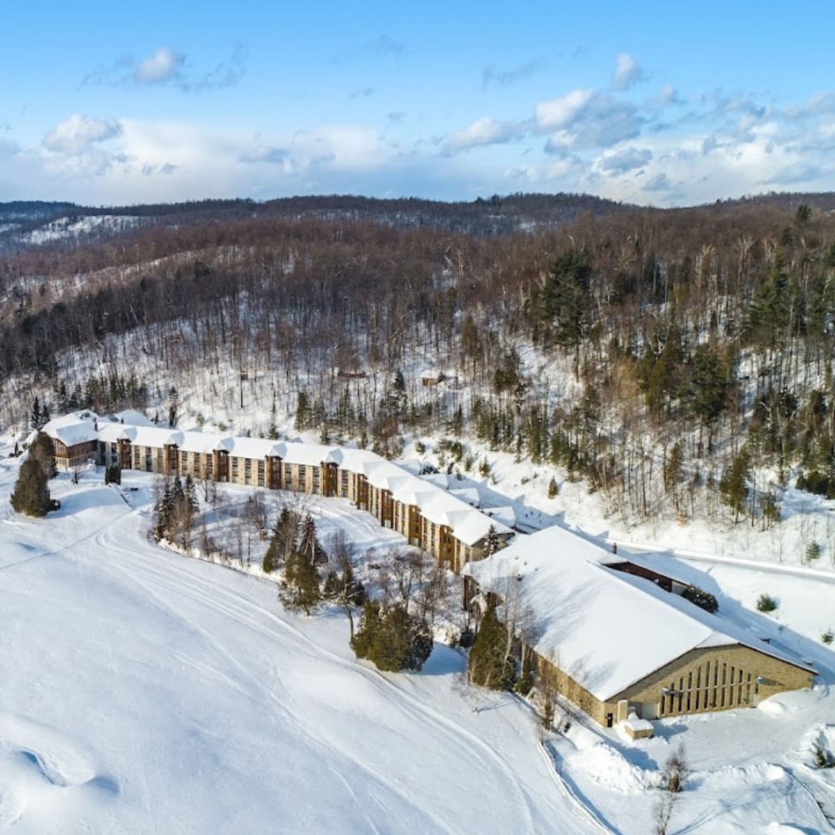 Vue aérienne de l’hôtel, entouré d’étendues enneigées et d’arbres dénués de leur feuillage.