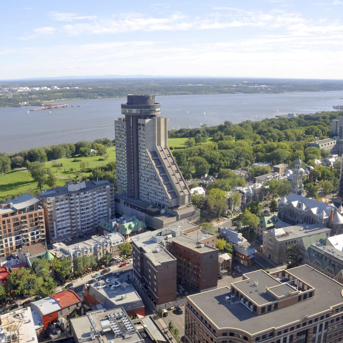L'Hôtel le Concorde à Québec vu de haut, avec les plaines d'Abraham et le fleuve en arrière.