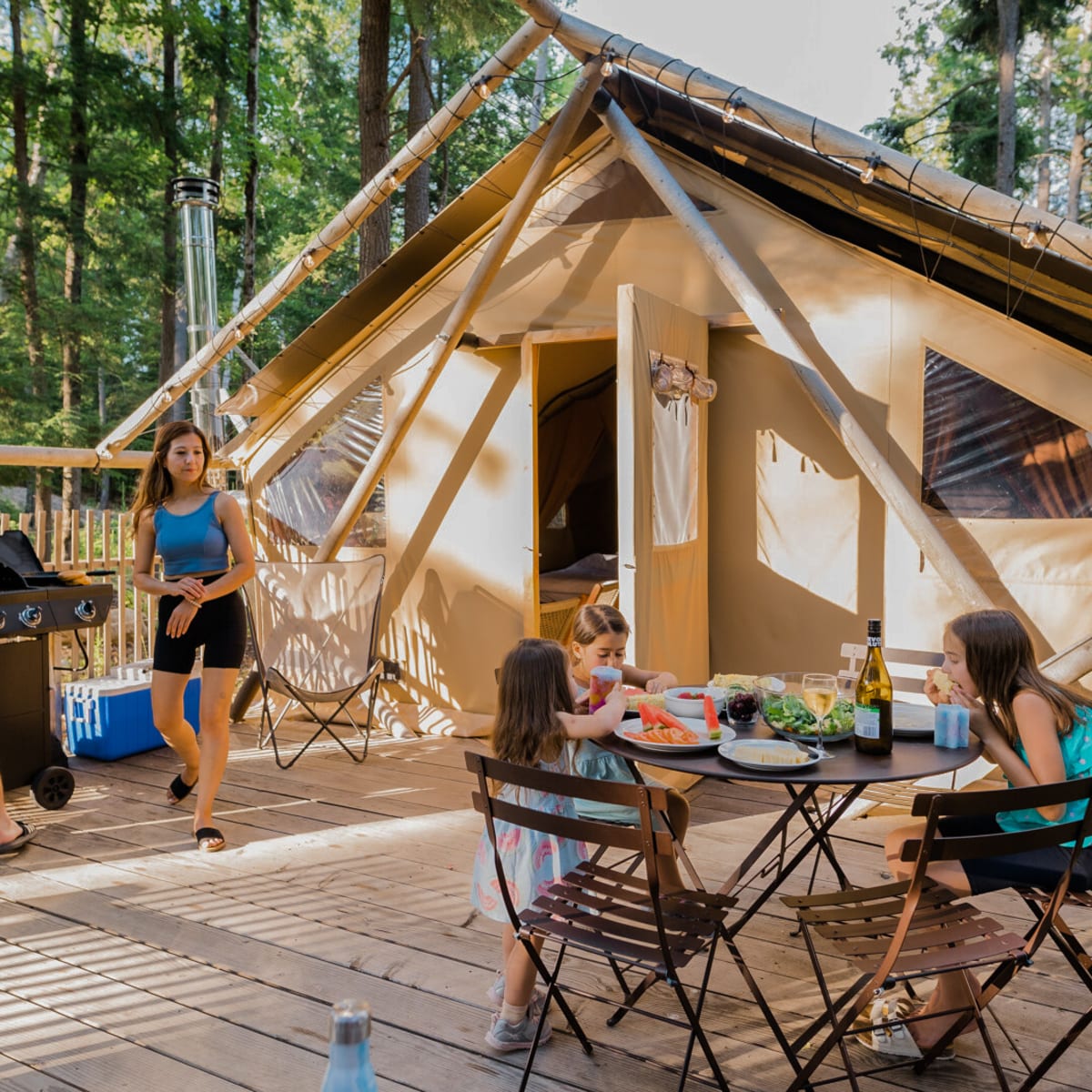 Family of four enjoying the sunshine on the terrace of their ready-to-camp tent.