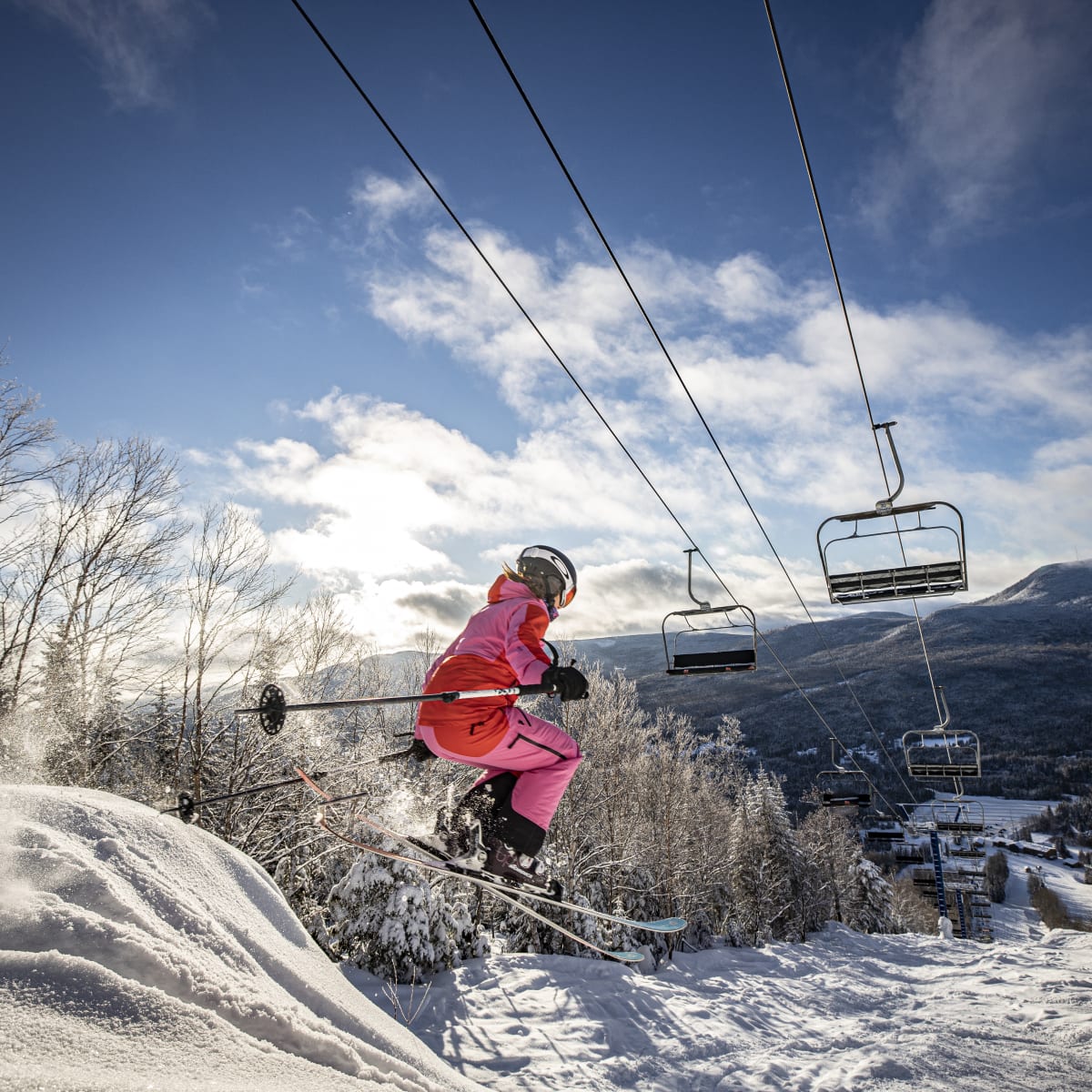 Skieuse qui fait un saut en-dessous de la remontée mécanique.