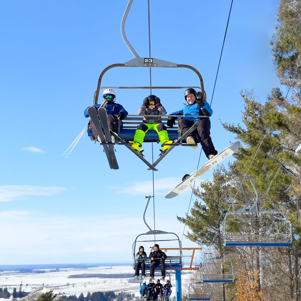 Father and two sons on a ski lift smiling at the camera.