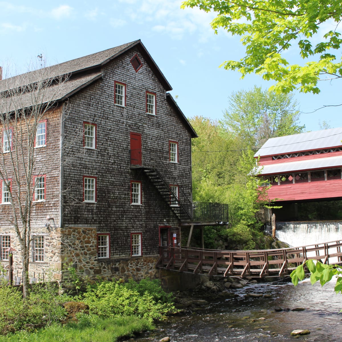 Extérieur du bâtiment ancestral, avec un petit pont en bois qui surplombe un ruisseau.