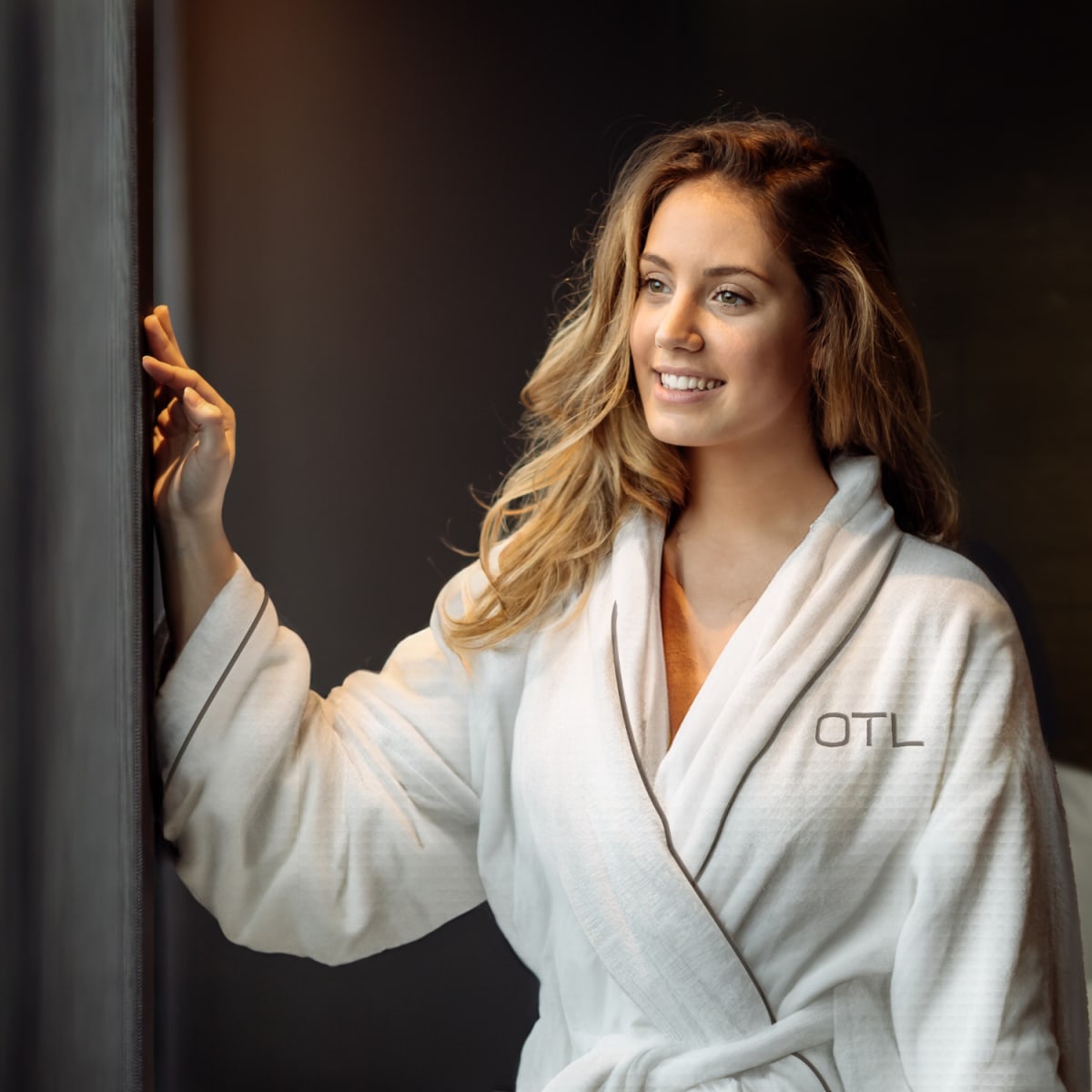 Woman in white bathrobe in a cozy-looking room.