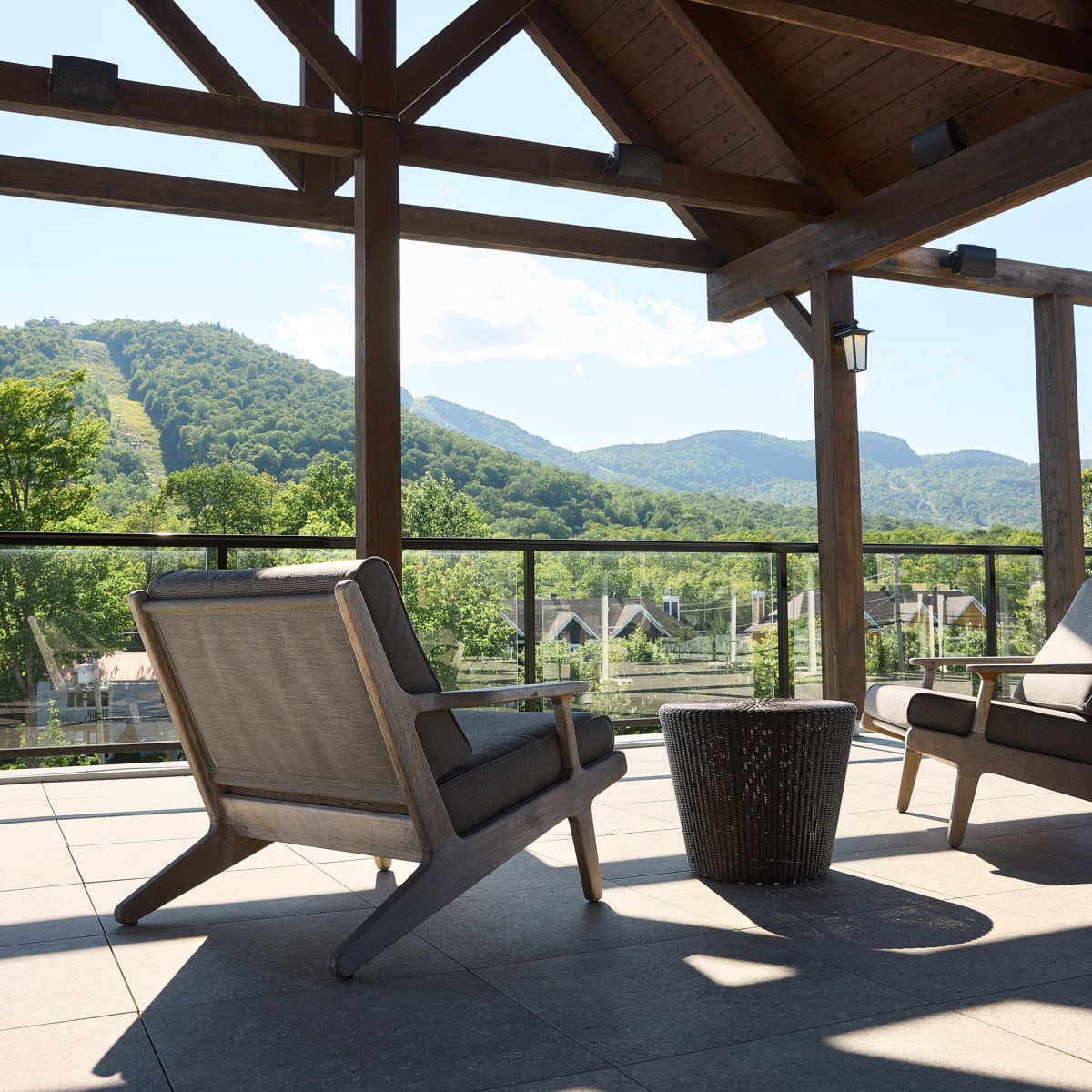 Une terrasse extérieure couverte, où se trouvent deux chaises confortables, donne sur un paysage montagneux.