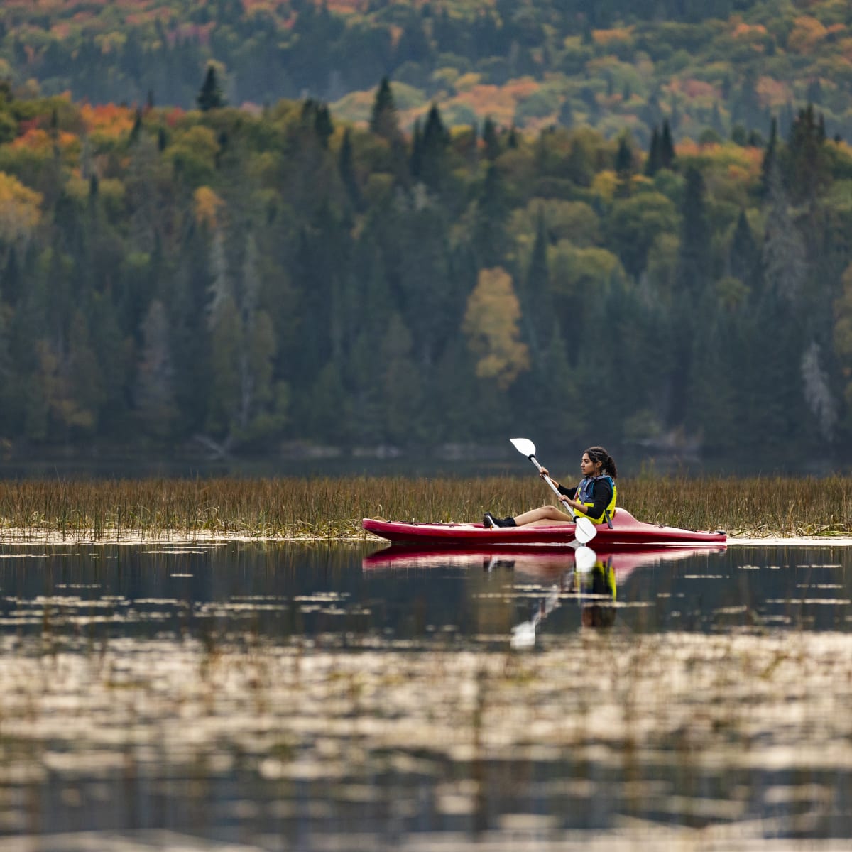 Young woman on a kayak on a lake in the Mont-Tremblant national park in the fall.