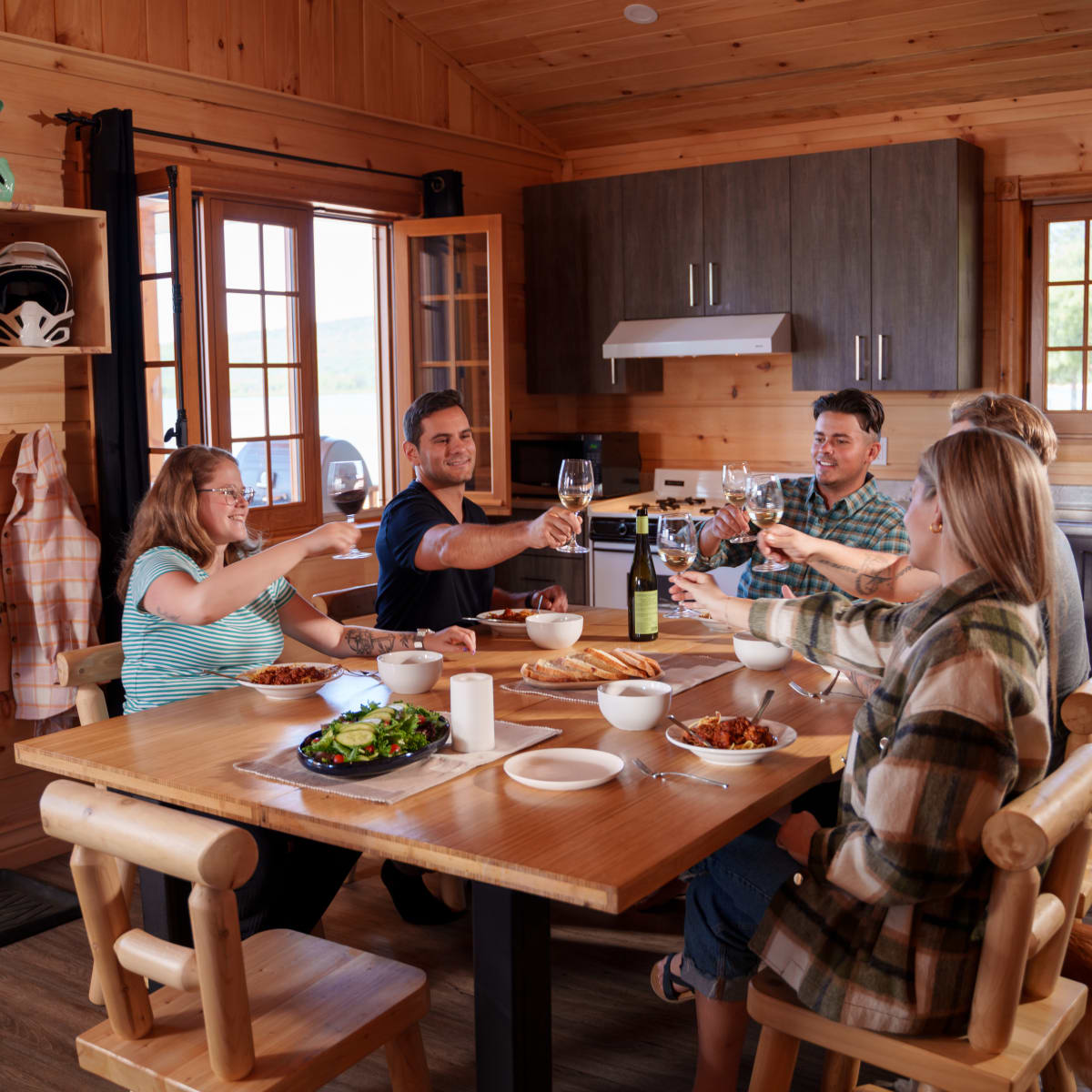 Group of diners around a table inside a wooden cottage.