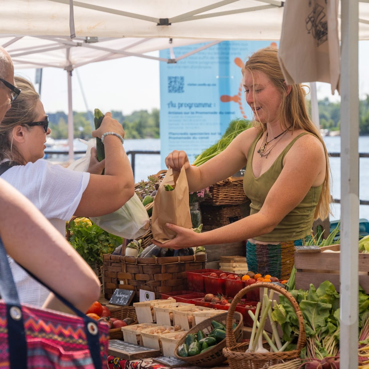 Booth at the farmer's market with customers lined up and merchant.