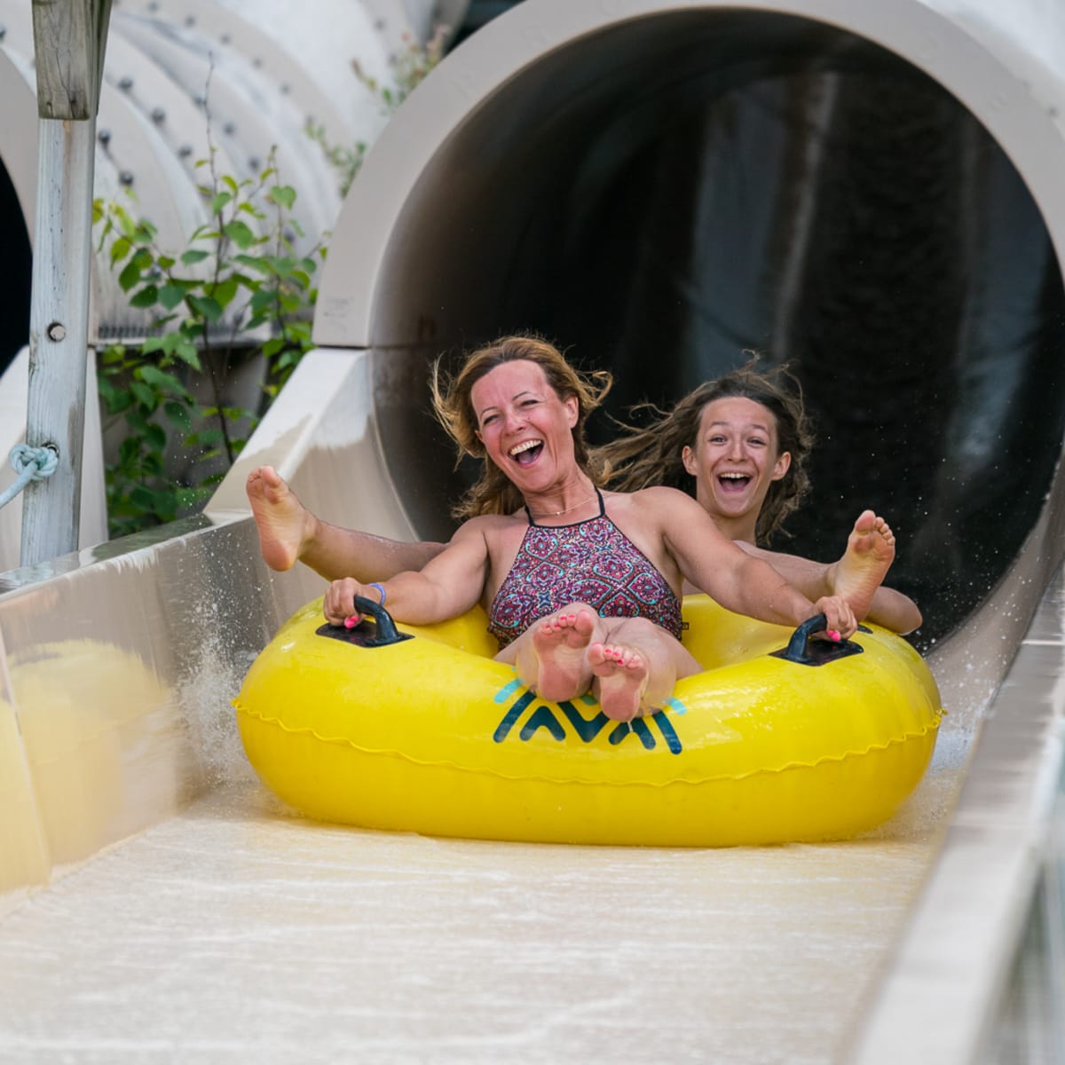 A smiling mother and teenager at the bottom of a water slide.