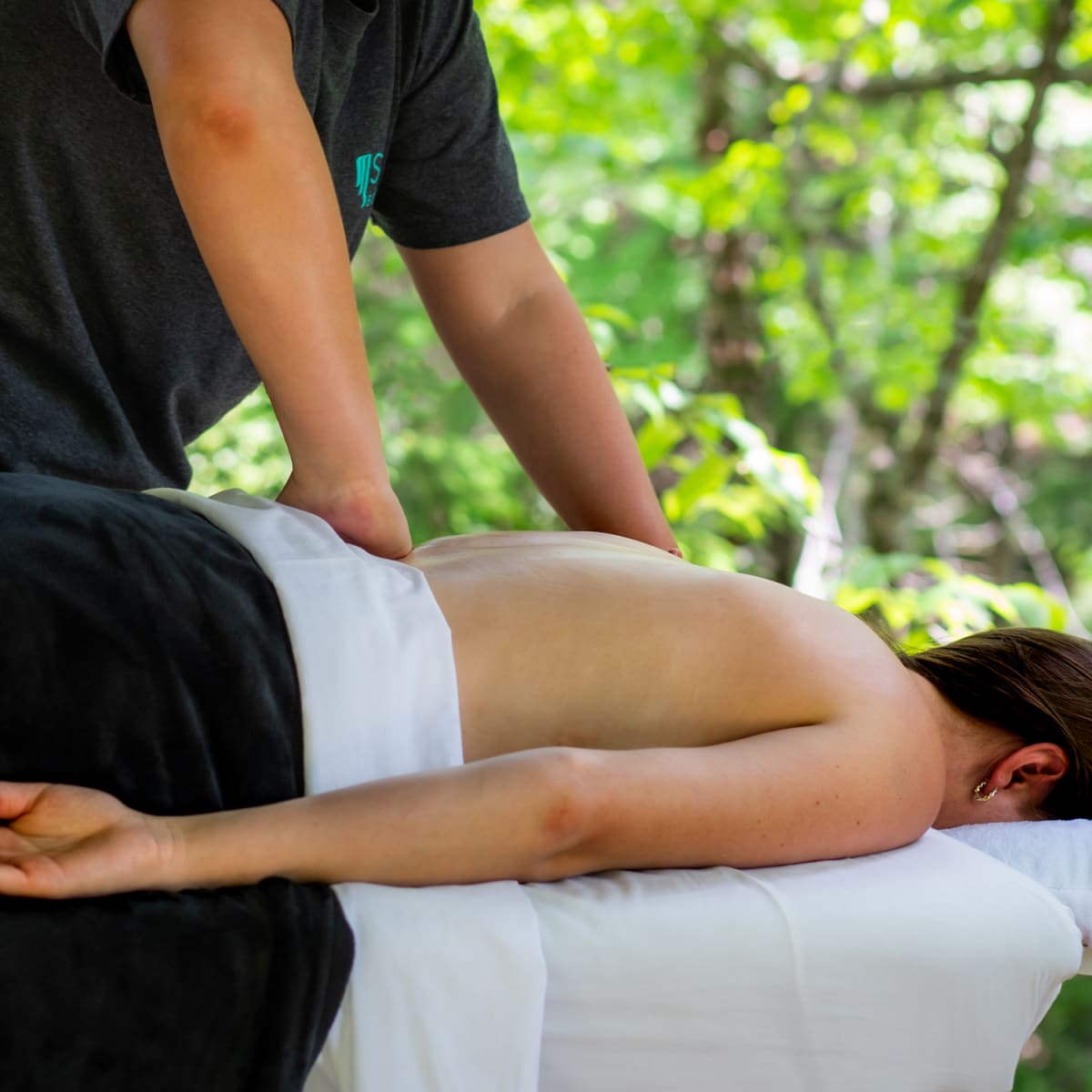 Femme en train de se faire masser le dos sur une table de massage.