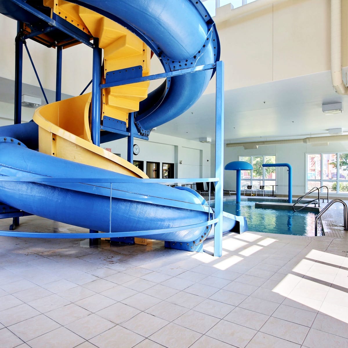 Indoor pool with blue and yellow slide at Super 8 Lachenaie.