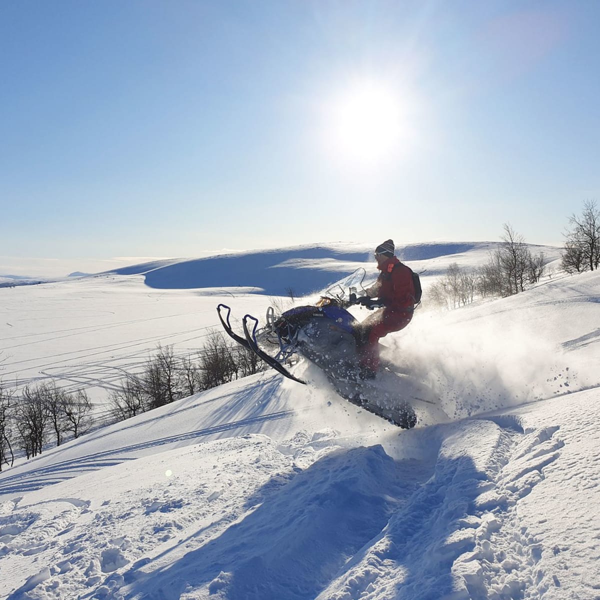 Person snowmobiling through a vast snow-covered landscape.