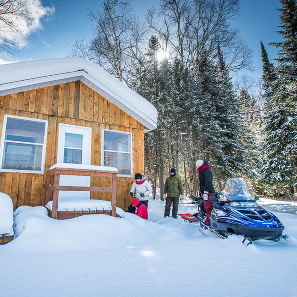 Chalet en hiver avec motoneigiste