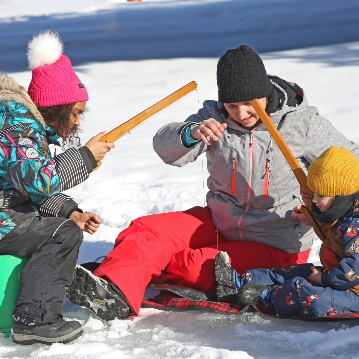 Parent et ses deux enfants à une activité de pêche sur glace.