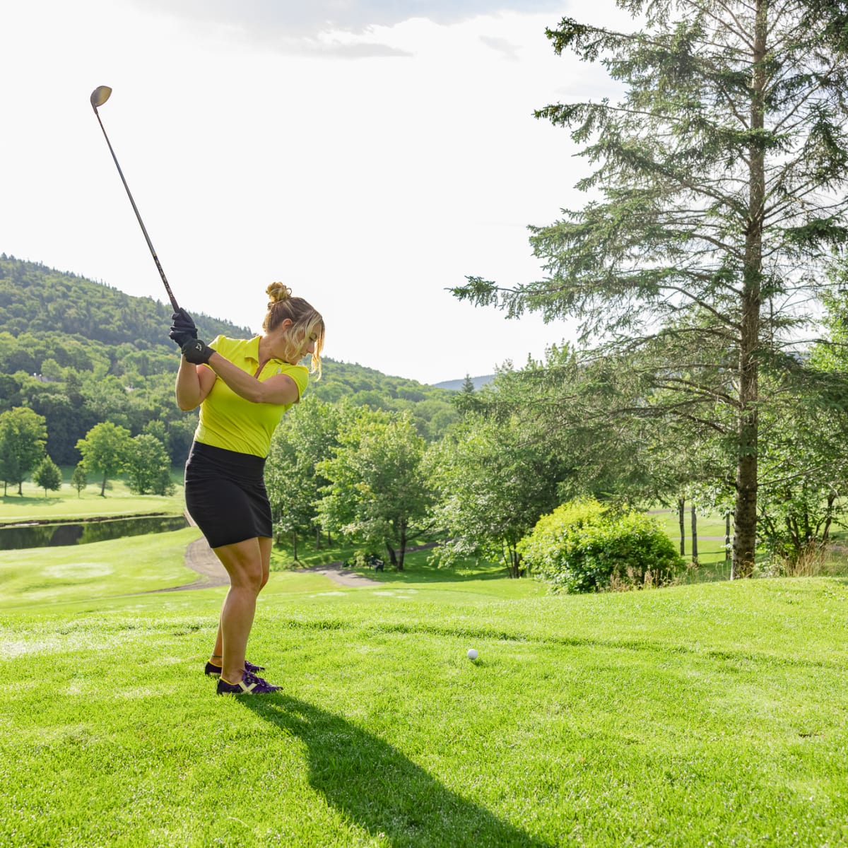Femme sur un terrain de golf s'apprêtant à frapper la balle. 