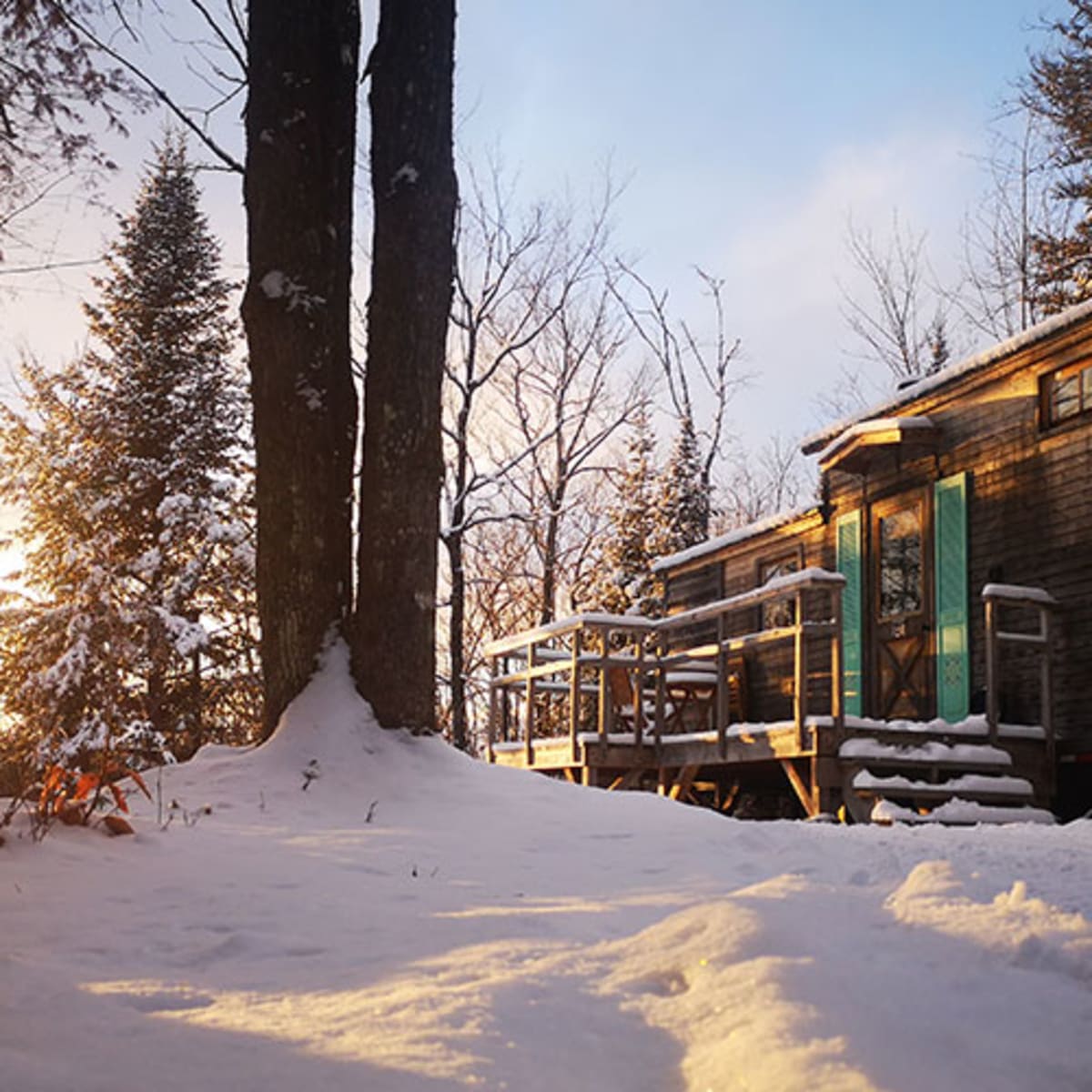 Mini-chalet dans un paysage enneigé sous une luminosité naturelle dorée.