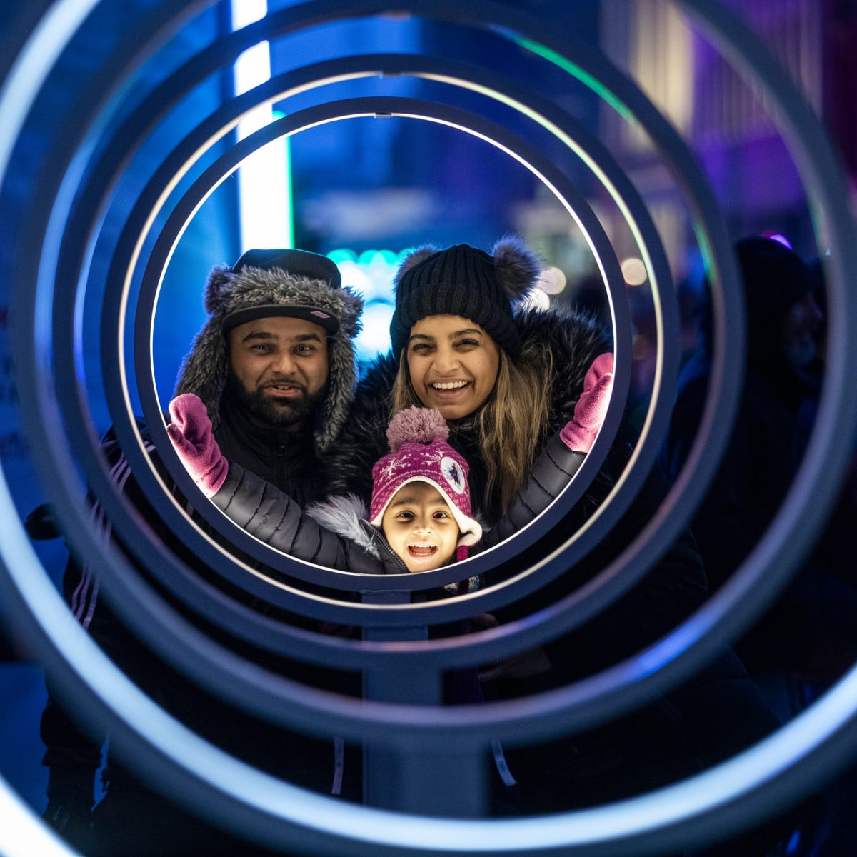Smiling father, mother and little girl admiring a luminous installation at Winterlude.