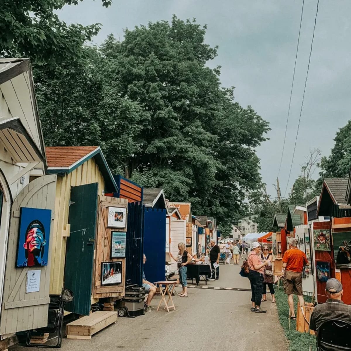 Ruelle bordée de petites cabanes dans lesquelles sont exposées des oeuvres d'art.