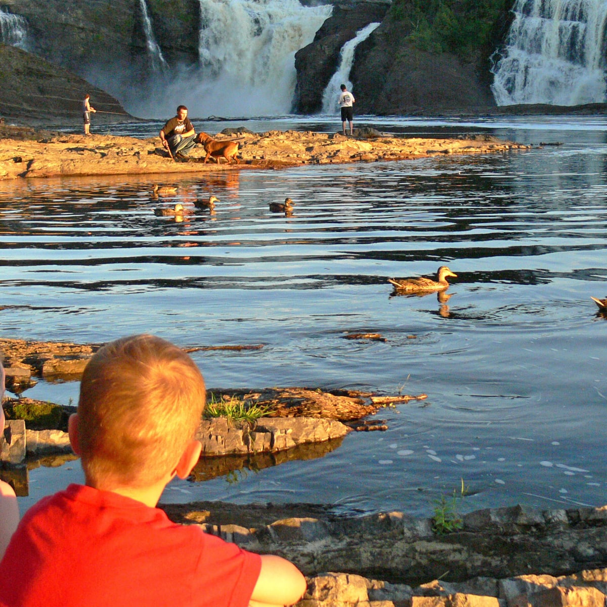 Two young kids sitting by the water at Parc des Chutes-de-la-Chaudière.