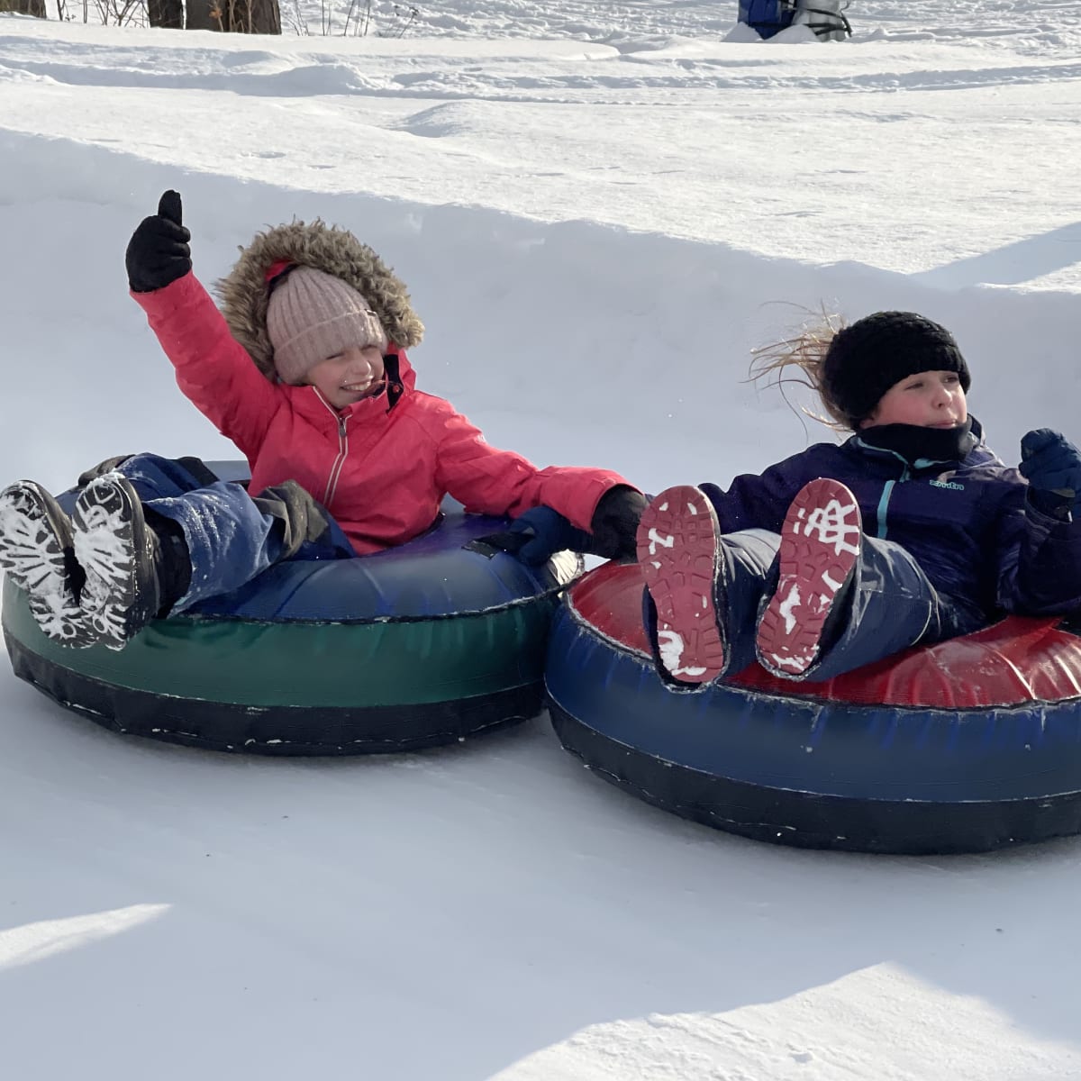 Two children sliding down on tubes.