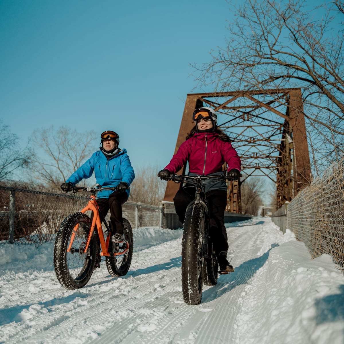 Two people on fatbikes on a snow-covered trail.
