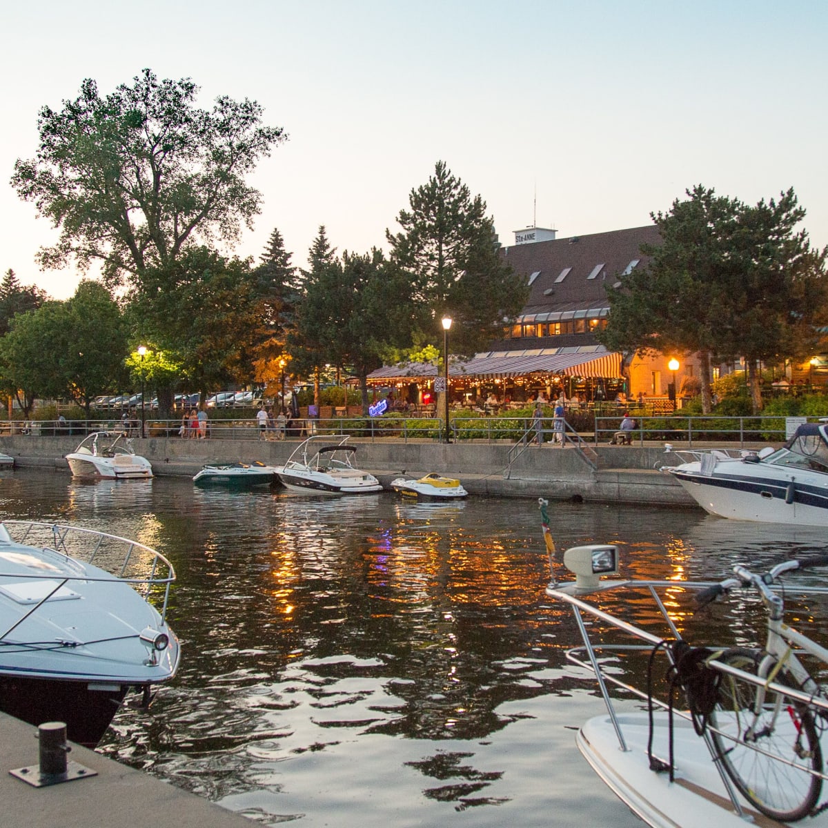 Waterfront with brightly lit shops and docked boats.