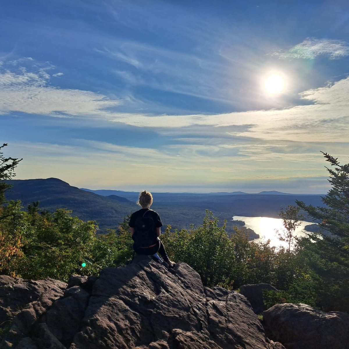 Femme au sommet d’une montage qui admire le paysage.