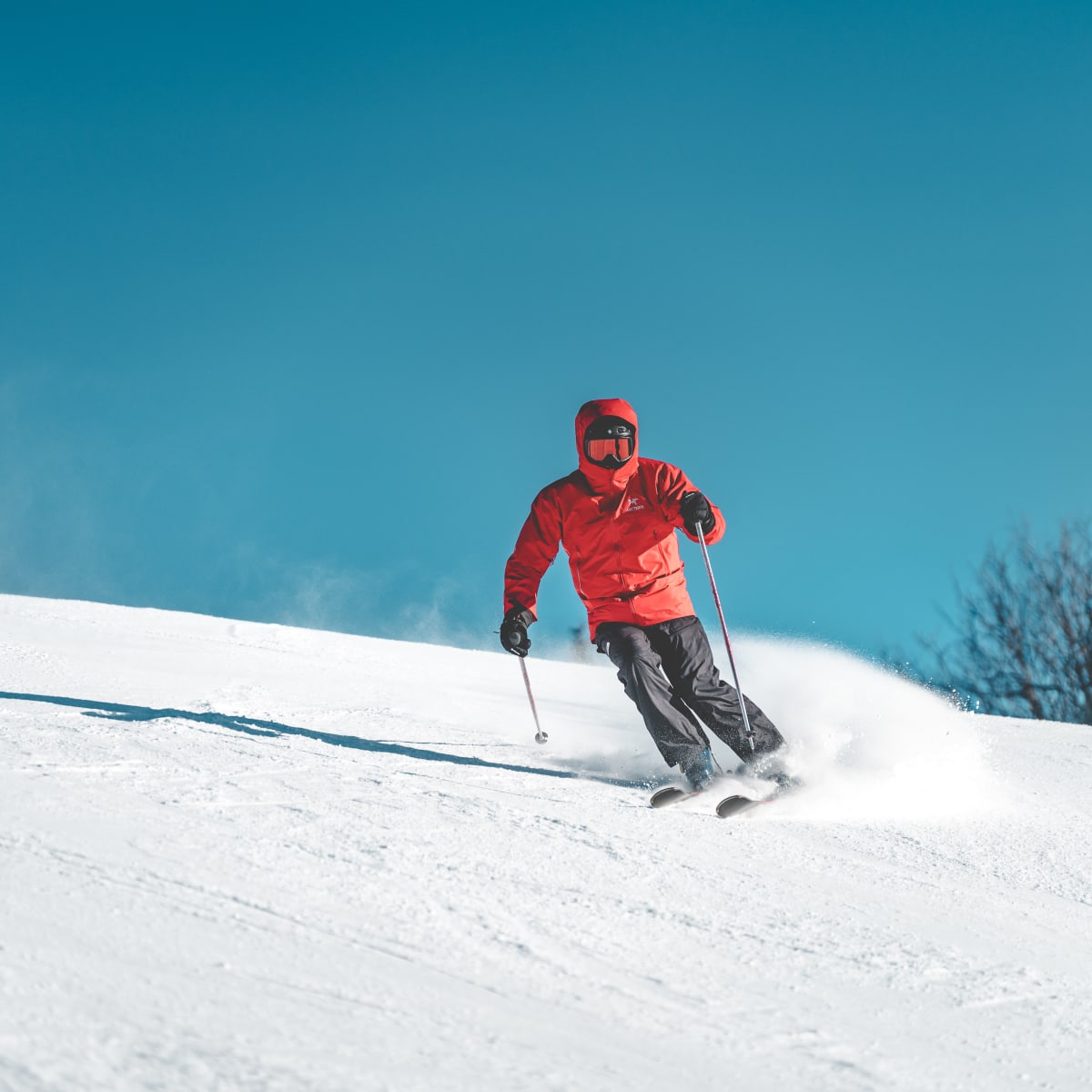 Personne en train de skier sur une pente, avec le ciel parfaitement bleu en arrière-plan.