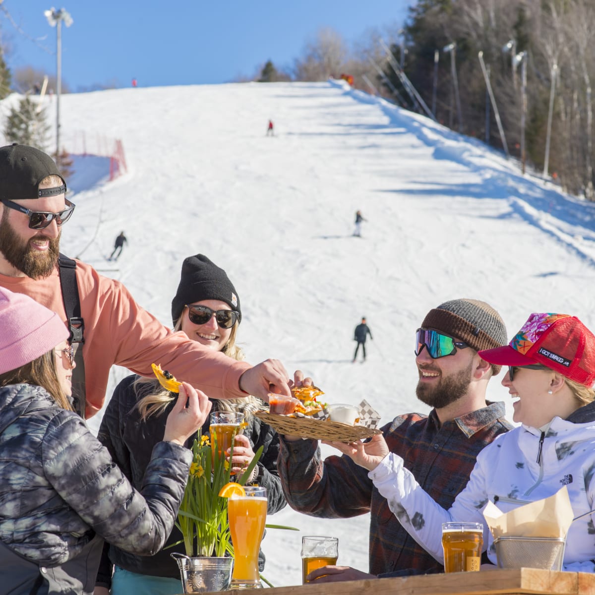 Des amis mangent au au bas de la montagne de ski du Sommet Saint-Sauveur.
