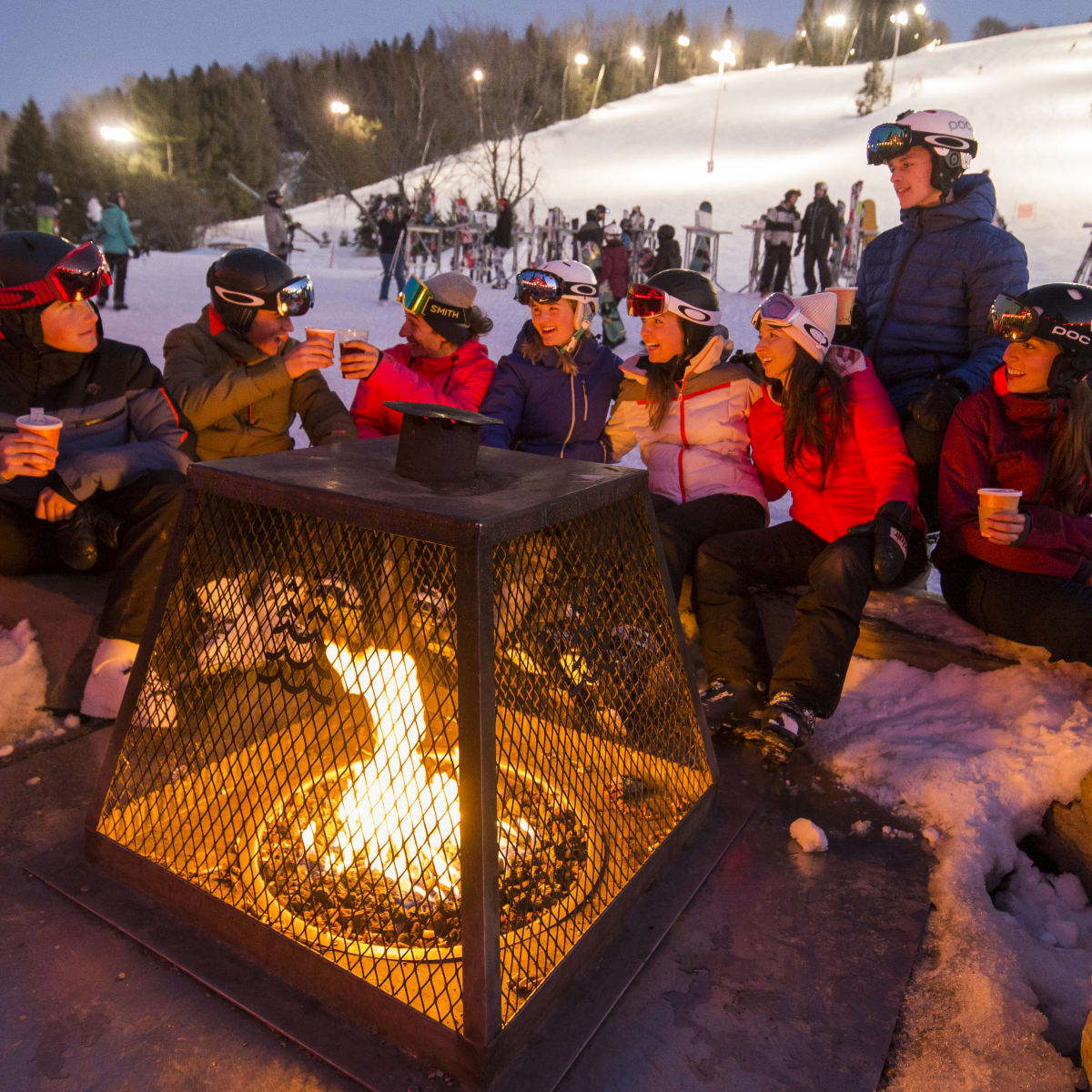 Des amis autour d'un feu au bas de la montagne de ski du Sommet Saint-Sauveur.