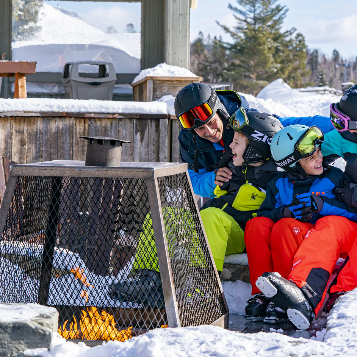 Une famille autour d'un feu au bas de la montagne de ski du Sommet Saint-Sauveur.