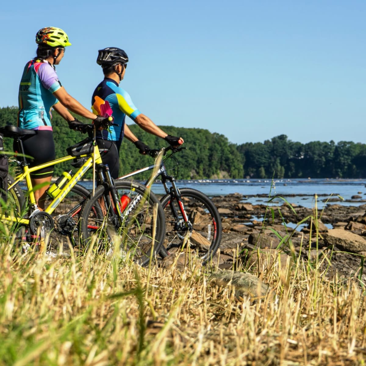 Couple à vélo sur le bord d'une rivière.
