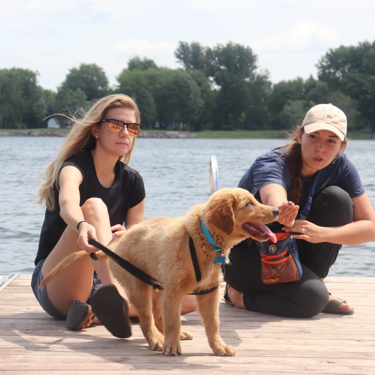 2 femmes et un chien sur un quai en été.